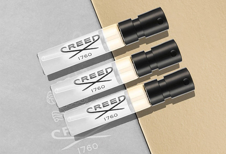 Three Creed perfume bottles on a gray and beige background