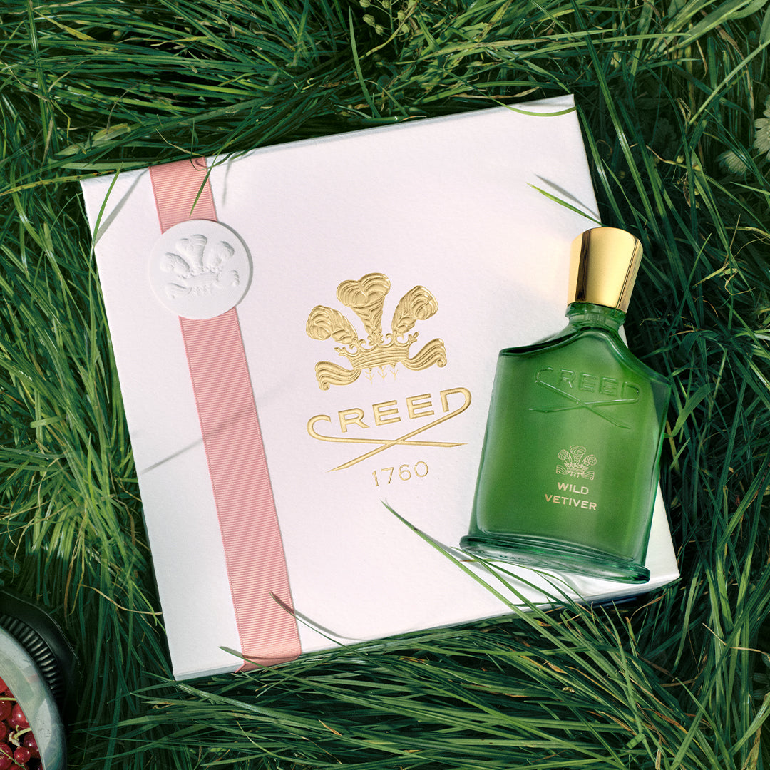 Green Creed perfume bottle with a white box featuring the brand logo on grass.