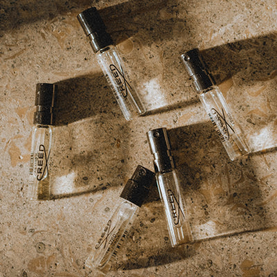 Creed fragrance sample vials elegantly arranged on a textured surface, highlighting exclusive member benefits.